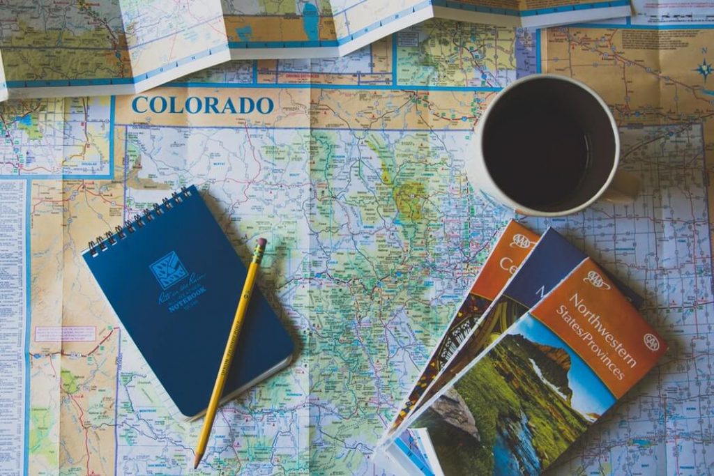 Bloco de notas, lápis e folders turísticos sobre mapa