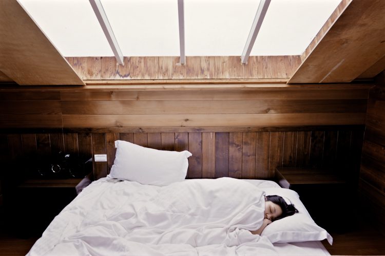 pessoa dormindo em uma cama com lençóis brancos
