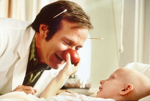 "Patch Adams" é um dos filmes ideais para os estudos em Medicina. Com nariz de palhaço, personagem interage com criança 