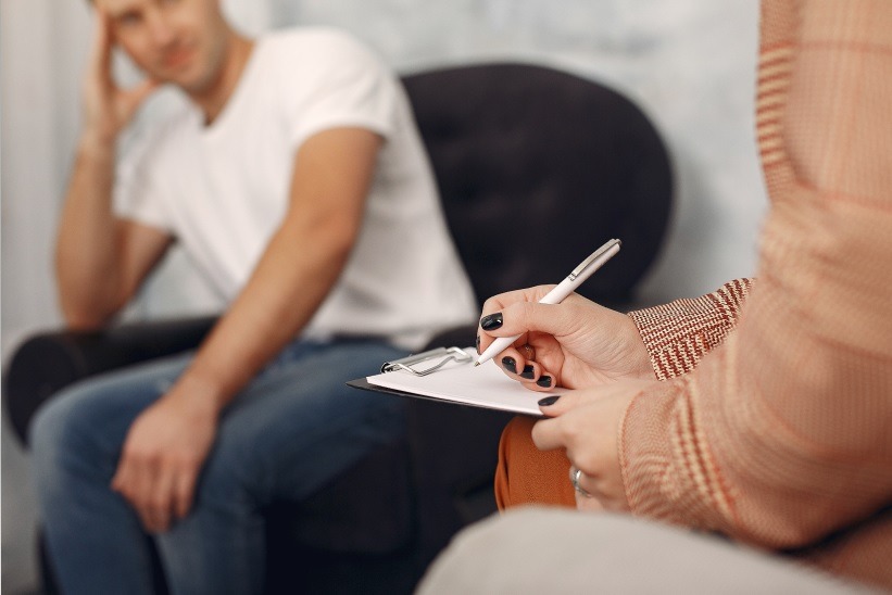 Homem sentado em cadeira de consultório de Psicologia 