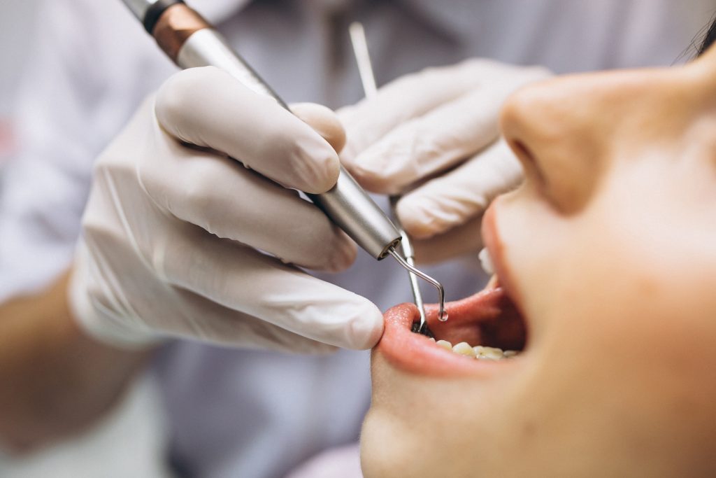 Dentista utilizando equipamentos na boca de paciente