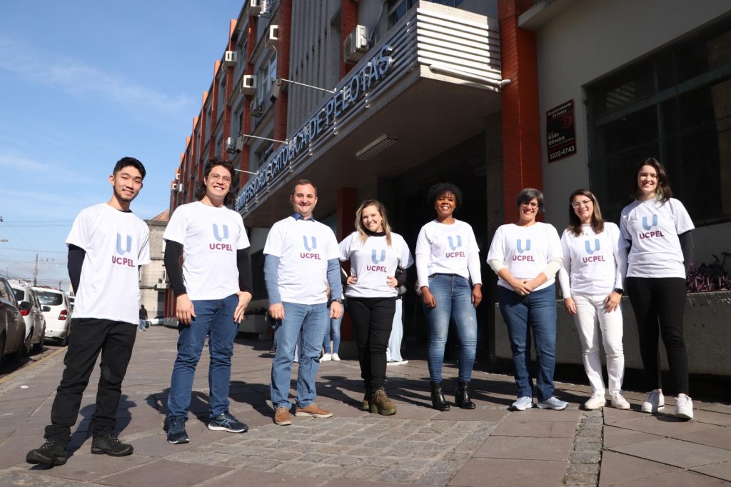 Colaboradores e alunos UCPel posam em frente ao Campus I com a camiseta da nova identidade visual